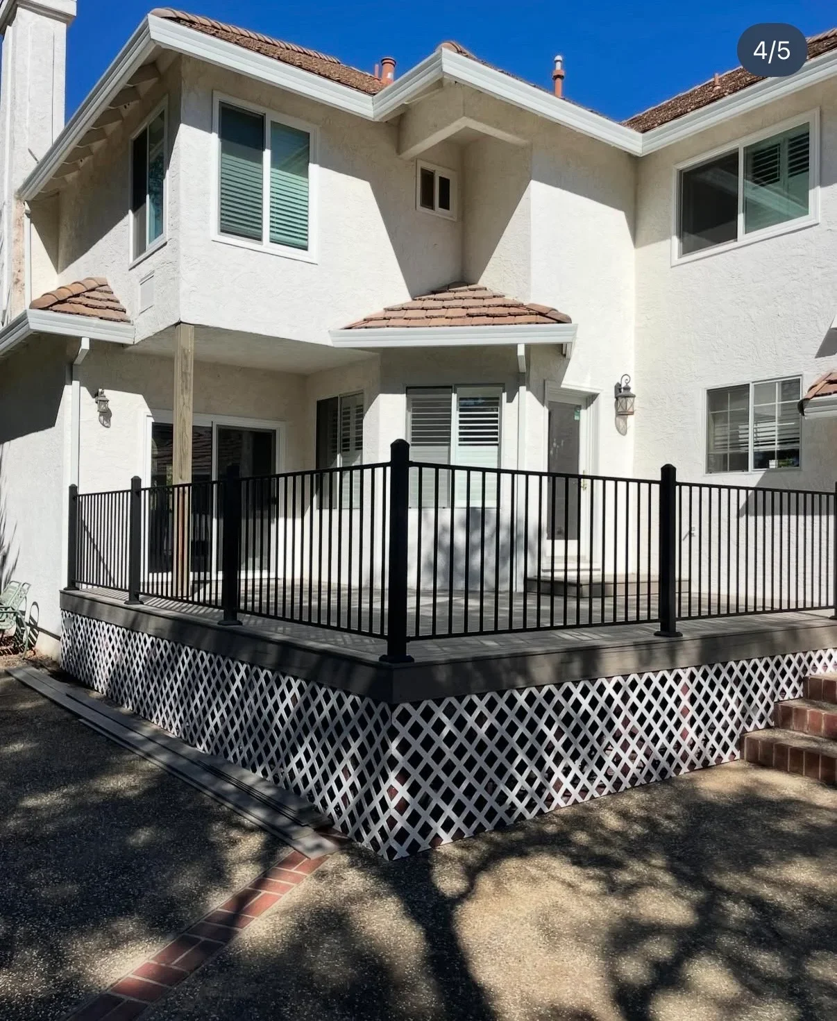 Black aluminum deck railing with white lattice skirting on two-level residential deck