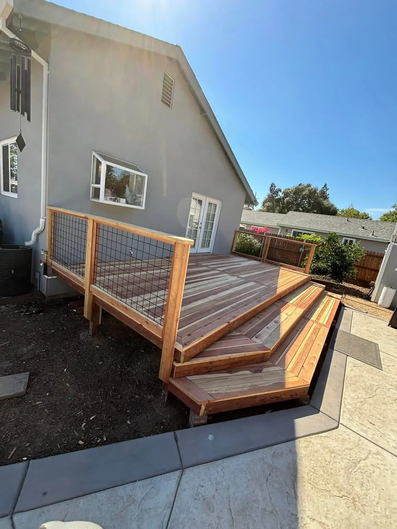 Multi-level composite deck with wood frame, cable railing, and stepped stairs