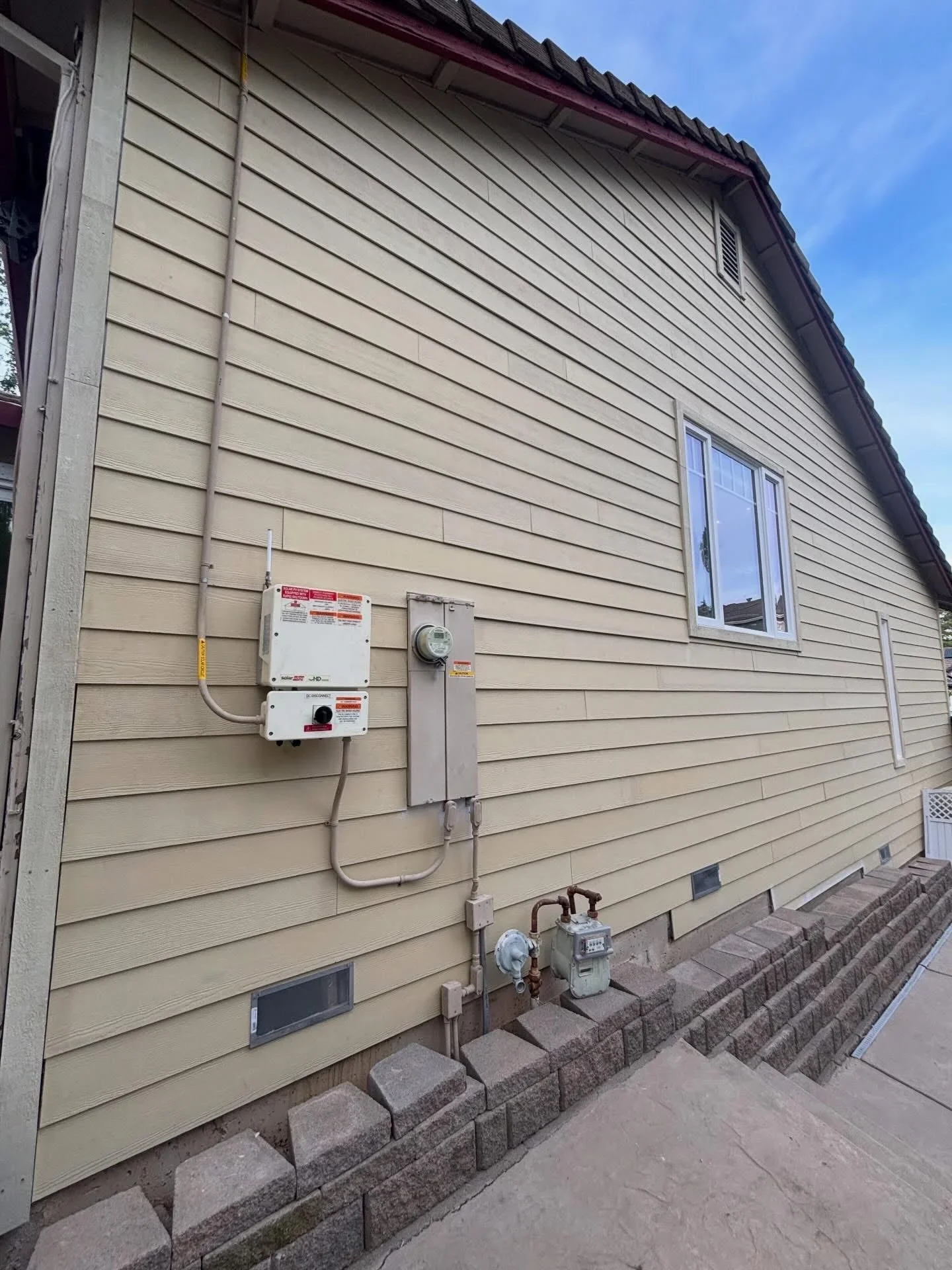 Concrete retaining wall blocks with electrical meter and service panel on vinyl siding