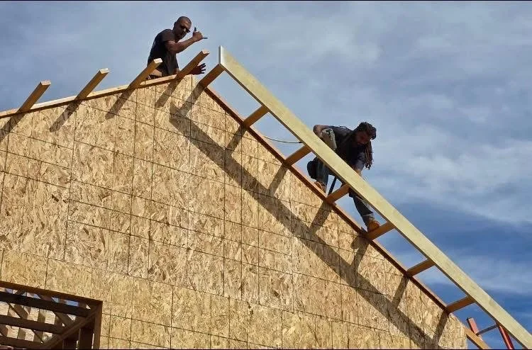 Roof framing with wooden trusses and OSB sheathing installation in progress