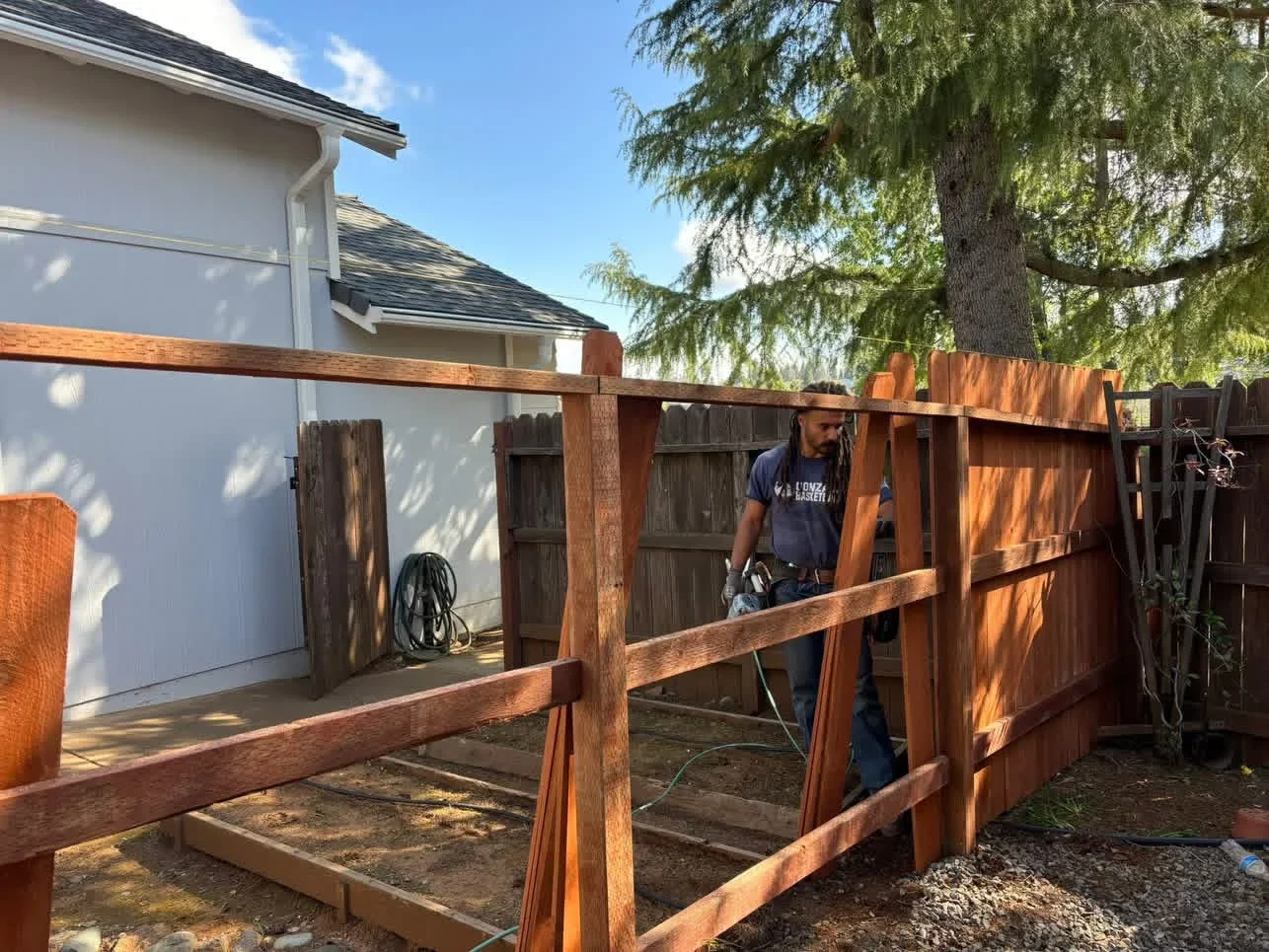 Wood deck with timber posts, beams, and railings under construction beside residential garage