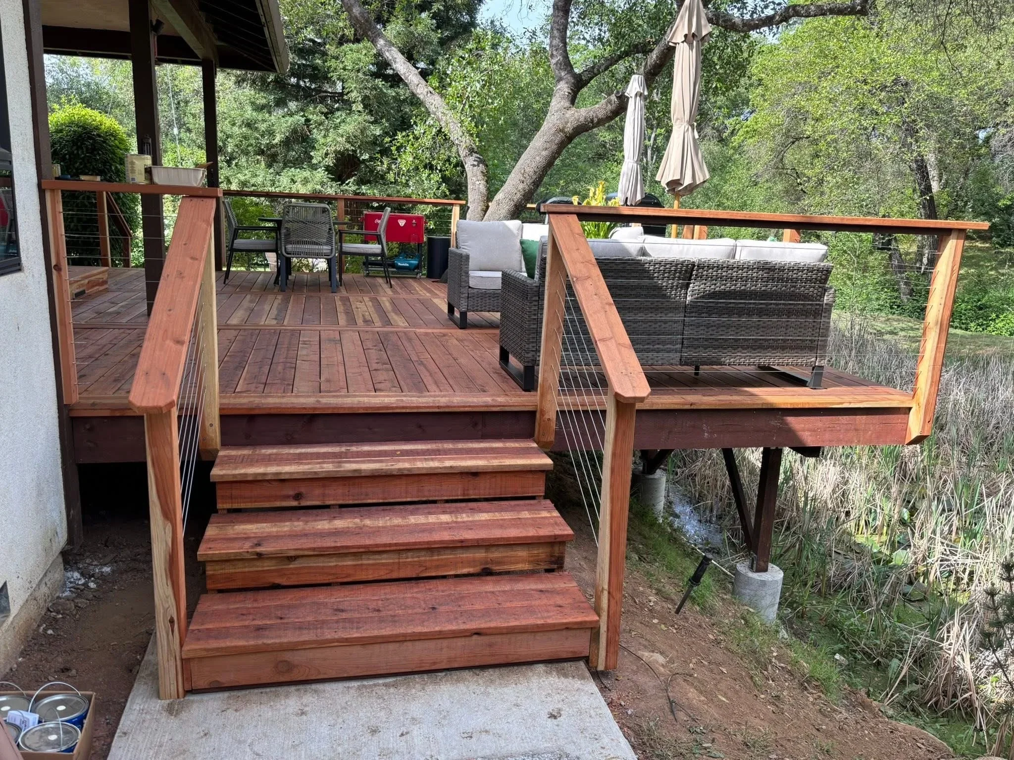 Composite deck with cable railings, built-in benches, and outdoor furniture overlooking trees