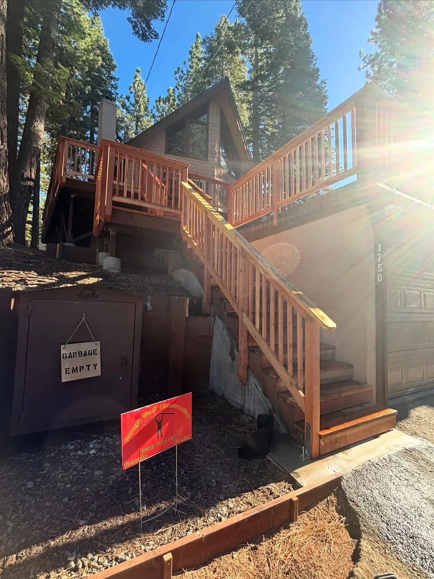 Multi-level redwood deck with staircase and railings on sloped terrain