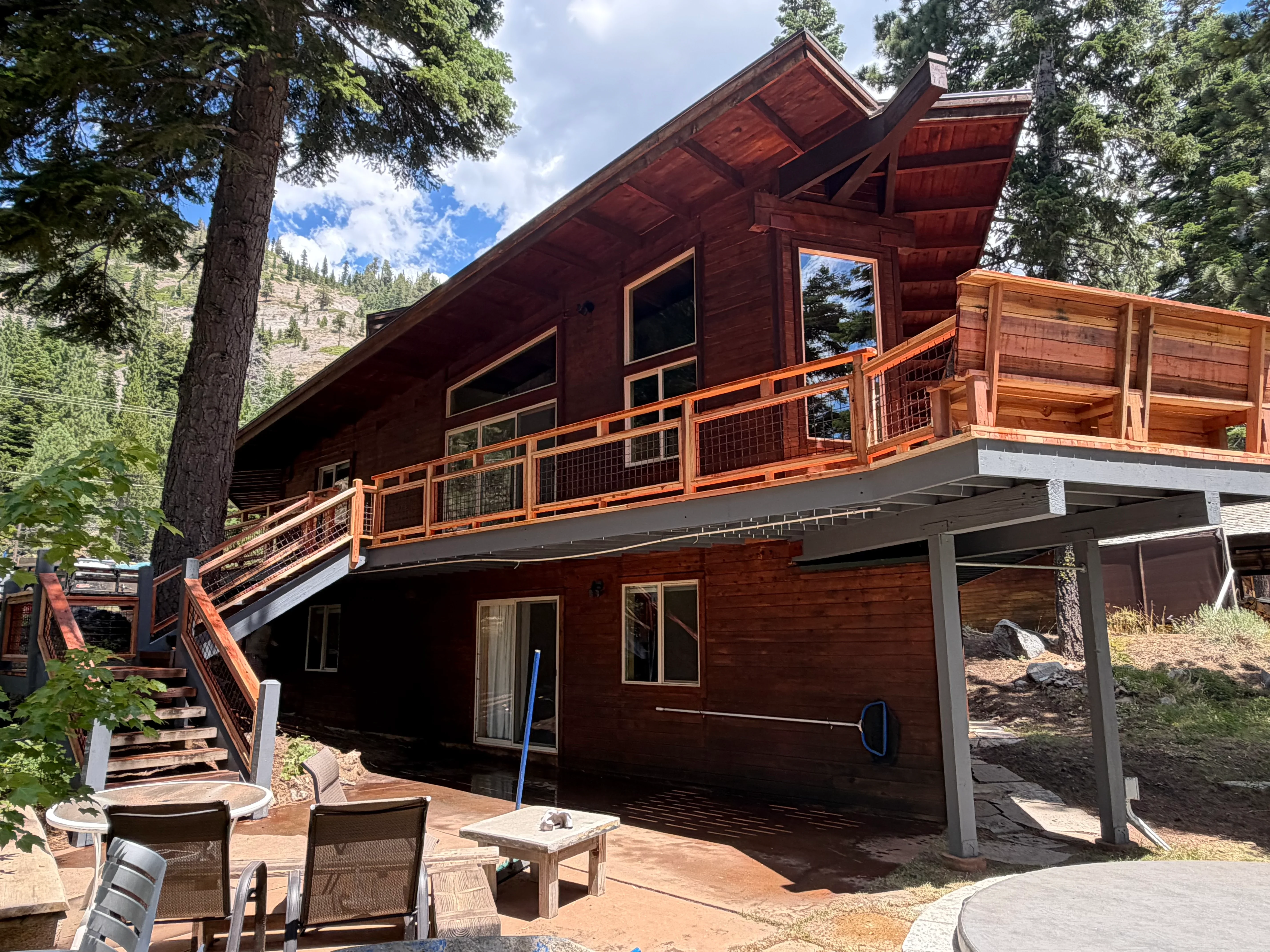 Two-level cedar deck with metal cable railings and covered patio area on mountain home