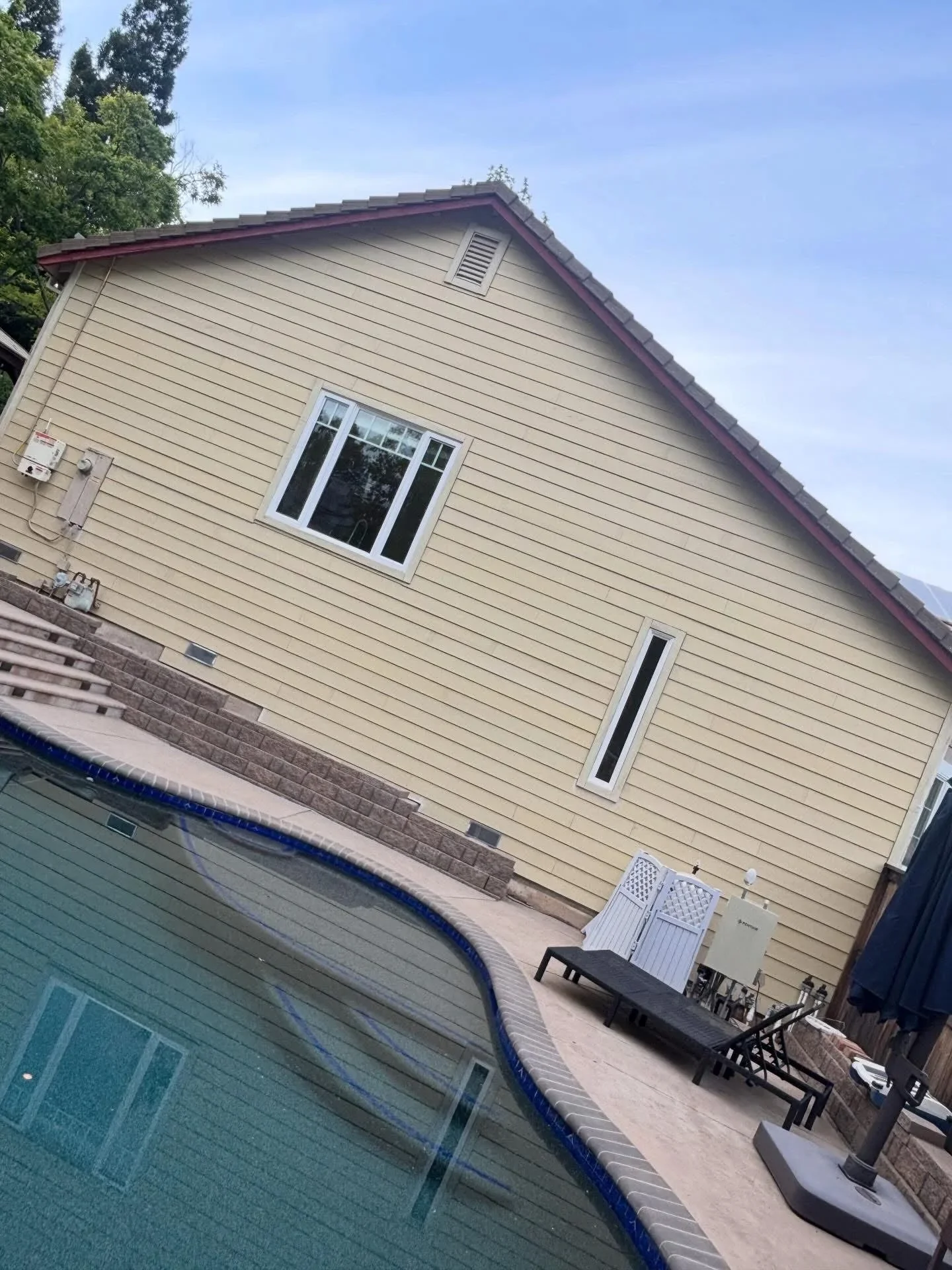 Cream vinyl siding with burgundy trim on residential home gable, new windows installed